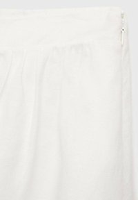 Tissu blanc avec une surface texturée, doté d'une taille froncée et d'une fermeture à glissière dans le coin supérieur droit.