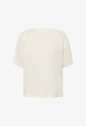 Blouse crème avec manches ballons ajourées, encolure ronde, fermeture par boutons au dos, et coupe ample.