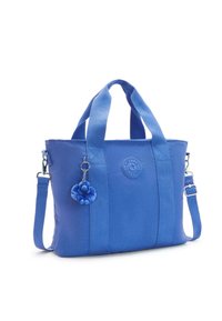 Borsa tote in tessuto blu con due manici superiori e una tracolla staccabile. Presenta un logo rotondo e un ciondolo a forma di scimmietta in peluche blu.