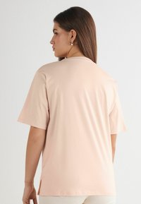 T-shirt a maniche corte, collo rotondo, di colore rosa chiaro, realizzato in materiale morbido. Presenta una vestibilità rilassata e fessure laterali all'orlo per maggiore comodità.