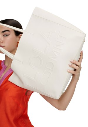 Bolso tote de cuero blanco con lettering en relieve "LOLA CSDMNT", con dos asas y un diseño estructurado. Textura suave, hardware mínimo.