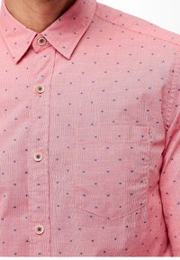 Camicia a righe rosse e bianche con piccoli puntini blu, dotata di colletto classico e tasca frontale. Tessuto strutturato, leggero.