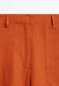Oranje linnen broek met een platte tailleband, twee zijzakken en gestikte details langs de naden. Licht, gestructureerde stof.
