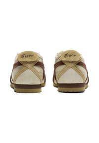 Sneakers con suede beige e accenti in tessuto marrone, caratterizzati da una punta rotonda, superficie testurizzata e un logo sul tallone.
