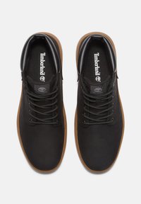 Svarta lädersneakers med gummisula, runda snören och vadderad krage; Timberland-logotyp på tungan och sidodetaljer.