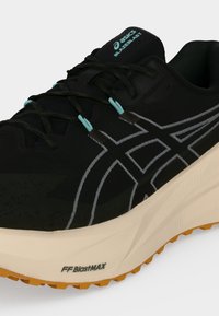 Chaussure de course Asics BlazeBlast noire avec semelle beige, œillets bleus et logo gris à motif sur le côté.