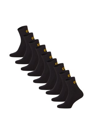 Huit chaussettes noires courtes disposées en rangée décalée, chacune avec des lettres jaunes au niveau du bord.