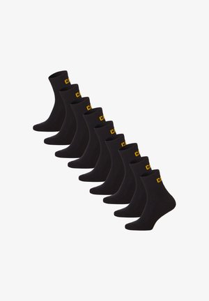 Acht schwarze Knöchelsocken, die in versetzter Reihe angeordnet sind, jeweils mit gelben Buchstaben am Bündchen.