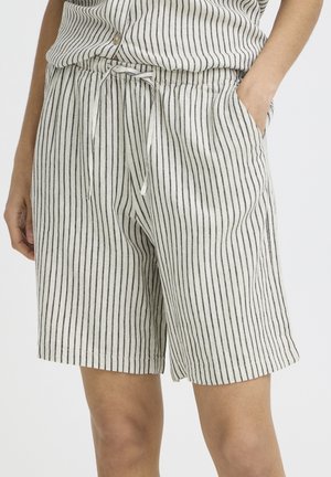 Białe lniane szorty z pionowymi czarnymi paskami, paskiem ściągającym w talii oraz kieszeniami po bokach, noszone razem z pasującą koszulą w paski.