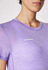 Maglietta atletica viola a maniche corte realizzata in tessuto leggero. Presenta un colletto rotondo e un logo bianco "MAMMUT" sul davanti.