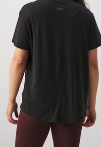 Czarny t-shirt z krótkim rękawem i okrągłym dekoltem, z subtelnym logo Nike na górnej części pleców oraz luźnym krojem.