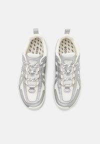 Grå og hvite joggesko med et mesh-oversydd, polstret krage og kontrasterende teksturerte snøringer. Designet med en forsterket tåhette og en trekkflik.