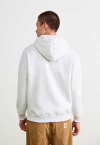 Lichtgrijze sweatshirt met een capuchon, met ribgebreide manchetten en zoom. De achterkant is eenvoudig, met een zachte textuur, gedragen met corduroy broek.