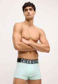 Mėtos žalios spalvos bokseriai su juodu Calvin Klein logotipo juostele, pasižymintys prigludusia forma ir švelnia audinio tekstūra.