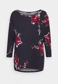 Top nero con maniche 3/4 caratterizzato da un motivo floreale rosso e bianco. Tessuto liscio e scollatura arrotondata con orlo leggermente curvo.