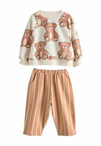 Lapsen kaksiosainen asu, jossa on kermansävyinen neuletakki, jossa on karhunprinttejä, ja vaaleanruskeat housut, joissa on valkoiset pystyradat ja etutaskut.