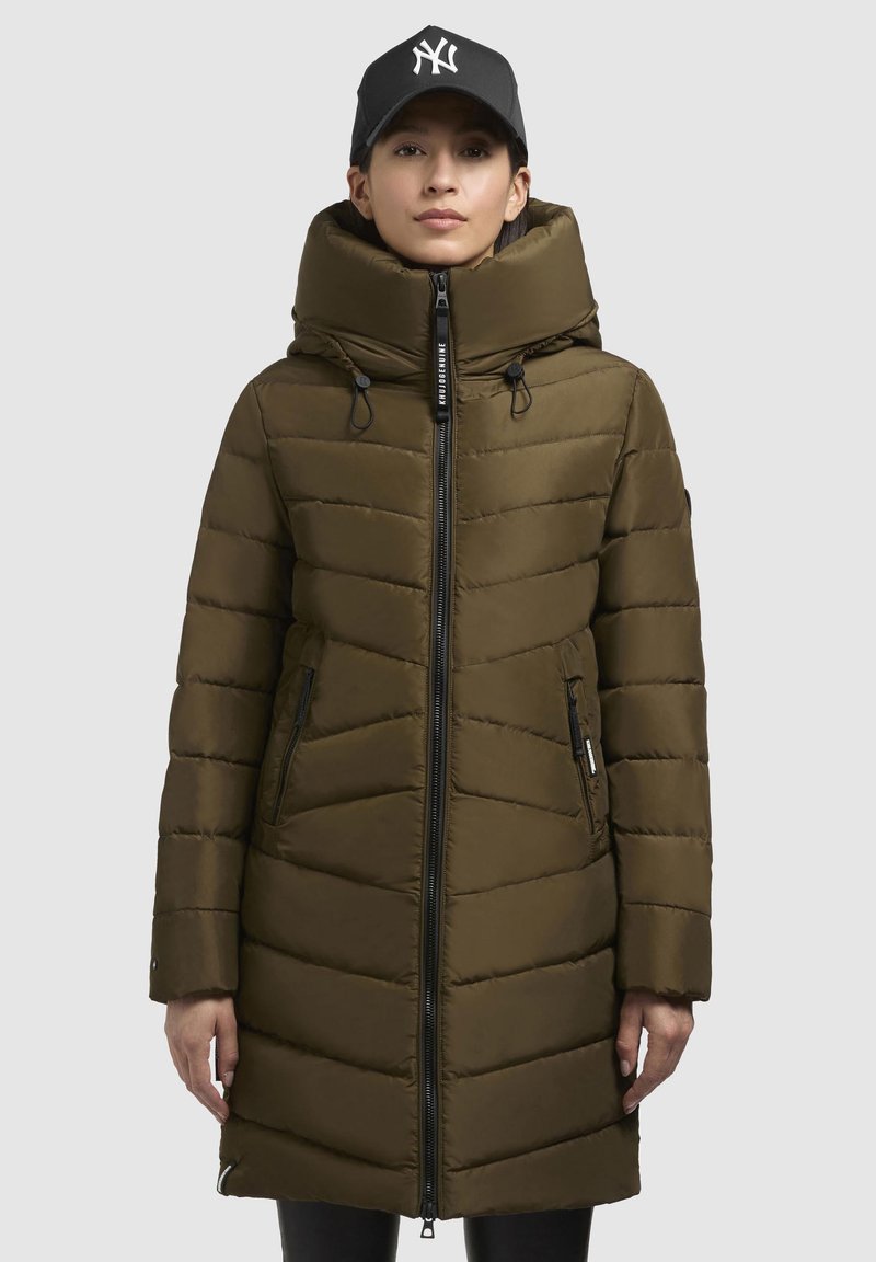 Manteau rembourré vert olive avec un col haut, design matelassé vertical, fermeture éclair et poches latérales. Comprend des cordons de serrage et une capuche.