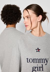 Felpa grigio con scollatura rotonda, caratterizzata da testo ricamato "tommy girl" e un logo a stella. Realizzata in morbido tessuto testurizzato.