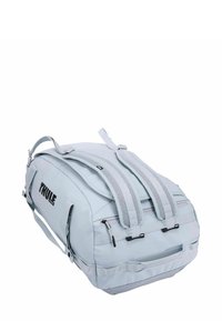 Thule rugzak in lichtblauw, met gevoerde schouderbanden, handvat aan de bovenkant, ritscompartimenten en duurzame stof. Rechthoekige vorm met merkvermelding.