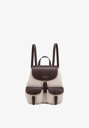 Sac à dos en tissu beige avec rabat en cuir marron foncé, bretelles, deux poches avant avec boucles et poignée supérieure, présenté sur fond blanc.