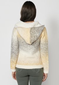 Stražnji pogled na hoodie s gradijentnim uzorkom u bijelim, žutim i sivim nijansama, mekanom teksturom i rebrastim manžetama.