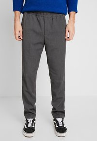 Szare, dopasowane spodnie z elastycznym paskiem w talii, o subtelnej fakturze. Połączone z czarno-białymi sneakersami na sznurowadła.