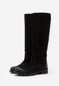 Bottes noires en daim montantes jusqu'au genou avec une finition lisse et texturée, bout arrondi et petit talon empilé. Elles présentent des détails cousus et un design simple.