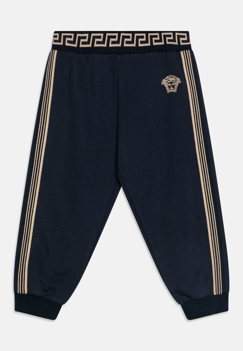 Jūras spēku sporta bikses ar elastīgu jostasvietu, kurām ir Grieķu atslēgas raksts un zeltainas lauvas galvas logotips kreisajā augšējā daļā.