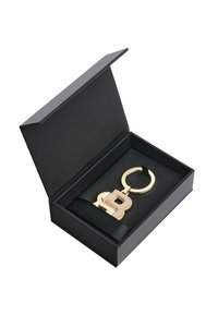 Gul nyckelring med en rosa "B"-design, presenterad i en svart presentask med ett svart satinband och en mjuk innerfoder.