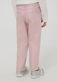 Różowe dżinsy o prostym kroju nogawki, z dwiema kieszeniami z tyłu i delikatnym teksturowanym wykończeniem, w połączeniu z srebrnymi trampkami.