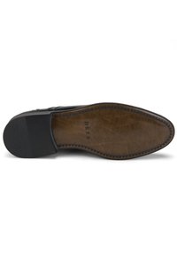 Semelle de chaussure en cuir noir avec une finition brune lisse. Présente un talon noir texturé et des coutures contrastantes le long du bord de la semelle intermédiaire.