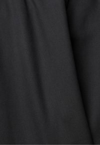Tissu noir avec une texture subtile de tissage diagonal et des plis doux créant des ombres douces.