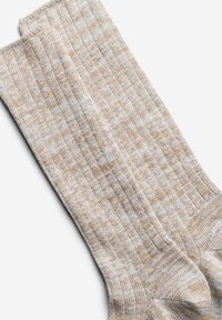 Stricksocken in Beige- und Cremetönen, die ein strukturiertes Muster mit einem gerippten Bündchen sowie verstärkten Zehen- und Fersenbereichen präsentieren.