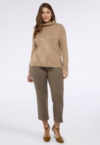 Béžový rolák se strukturovaným designem a flitry, spárovaný s hnědými strukturovanými zkrácenými kalhotami a hnědými vysokými podpatky.