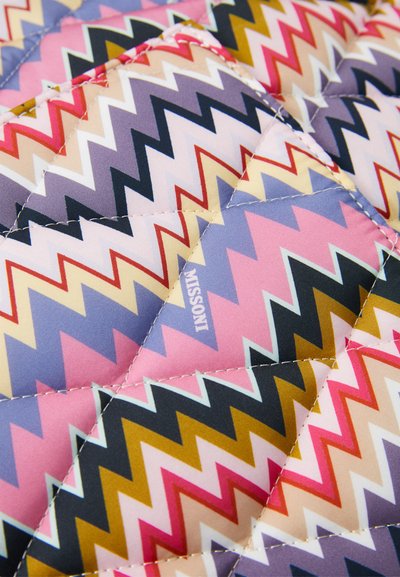 Taflă matlasată cu un model zigzag multicolor în roz, mov, bej, roșu și muștar, arătând forme de diamant cusute și textul "Missoni".