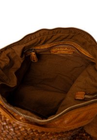 Open bruine leren tas met zicht op de voering van stof en een klein ritsvak met een leren trekker en een gestempeld label.