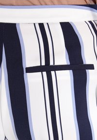 Pruhované kalhoty v námořnické modré, světle modré a bílé barvě, s kapsou na zadní straně, z polyesterového materiálu a přiléhavým střihem.