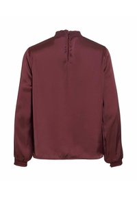 Langærmet, mørk bourgognebluse med rynkede manchetter og en flæsebesat krave med knaplukning bagpå.