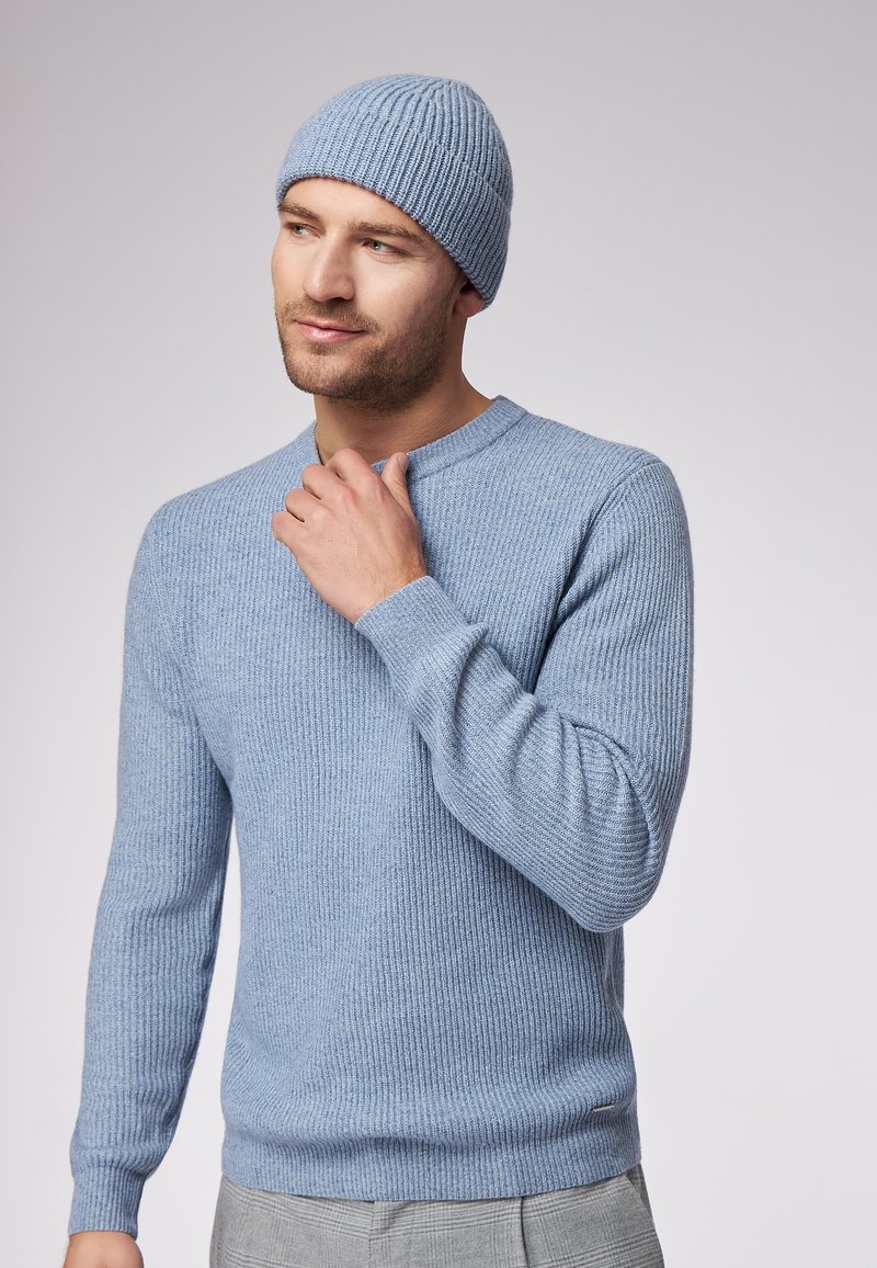 Maglione a coste blu chiaro e berretto coordinato realizzati in materiale morbido. Il maglione presenta un collo a giro e maniche aderenti.