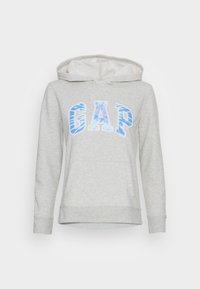 Sudadera con capucha de color gris claro con cordón ajustable, con un bolsillo frontal y un logo gráfico azul de "GAP". Textura suave y diseño casual.