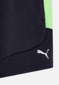 T-shirt en tissu bleu marine avec un accent texturé vert clair, ourlet arrondi et petit logo Puma blanc près du coin inférieur gauche.