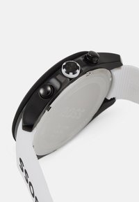 Black watch with a round case, textured black and white strap, two push buttons, and a silver back featuring the "BOSS" logo.
