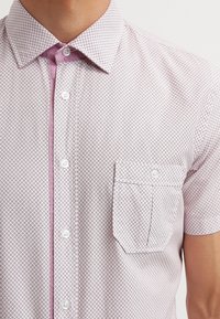 Korte mouw knopshirt in lichtroze met een geometrisch patroon, met een contrasterende kraag en een borstzak aan de linkerkant. Soepele textuur.