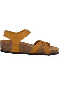Sandalias de cuña de cuero marrón con tiras cruzadas, correa ajustable en el tobillo y suela de corcho texturizado. Diseño de perfil bajo con plantilla suave.
