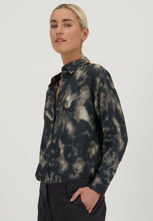 Chemise à manches longues avec des boutons en noir avec un motif tie-dye gris et crème. Présente un col classique et une coupe décontractée, fabriquée en tissu lisse.