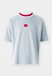 Svijetlosiva majica kratkih rukava s rebrastim ovratnikom koja sadrži crvene i bijele pruge. Središnji crveni kvadratni aplikacija s logotipom "HUGO". Mekana tekstura tkanine.