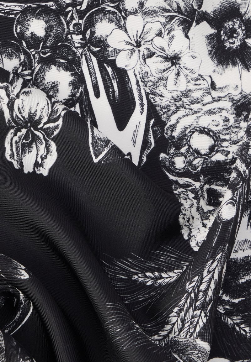 Schwarzer Stoff mit einem detaillierten weißen Blumenmuster, das komplexe Designs von Blumen, Früchten und Blättern zeigt.