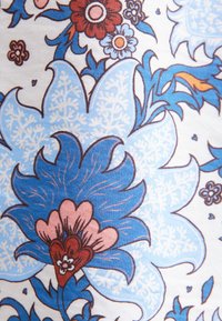 Tessuto floreale con grandi fiori stilizzati blu con accenti rosa e rossi su uno sfondo bianco; motivi intricati e foglie.