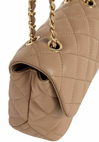 Beżowa torebka skórzana pikowana z łańcuszkami w złotym odcieniu i detalami z oczkami. Charakteryzuje się miękką fakturą i zarysowanym kształtem.