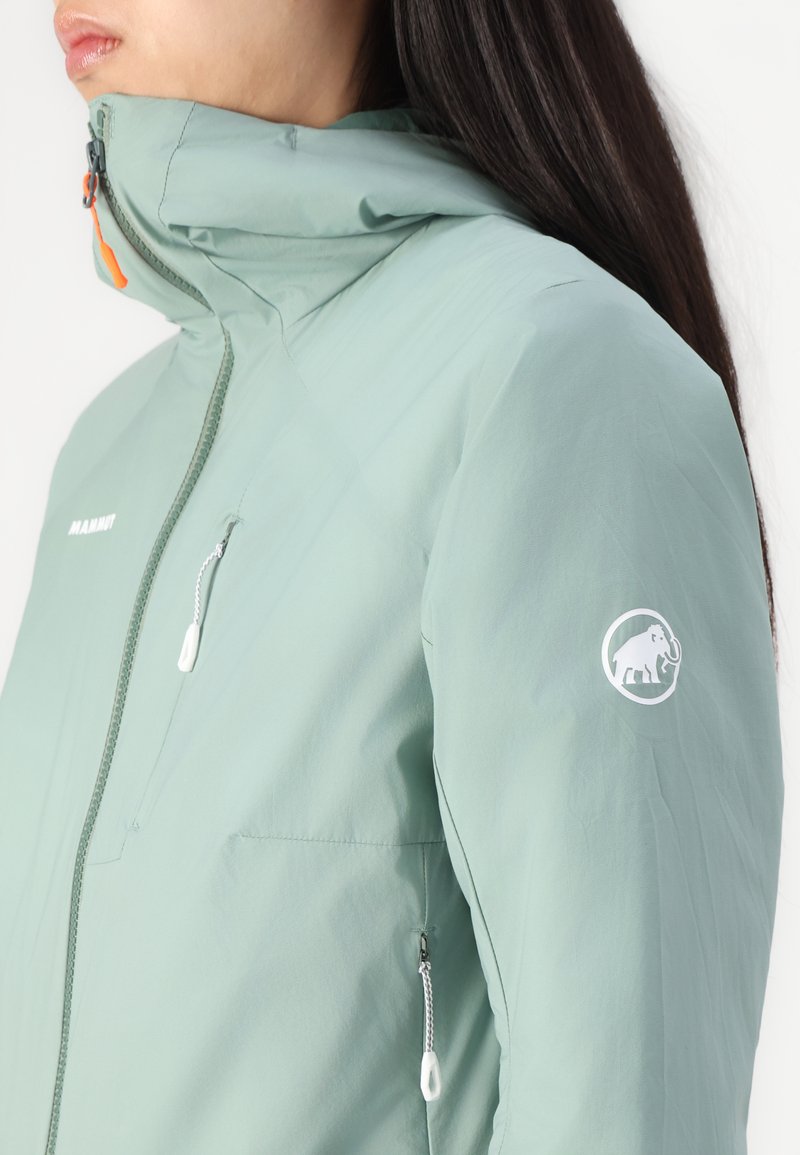 Jasnozielona wodoodporna kurtka z wysokim kołnierzem, suwakiem z przodu i jedną kieszenią na zamek na klatce piersiowej. Posiada biały logo na rękawie.